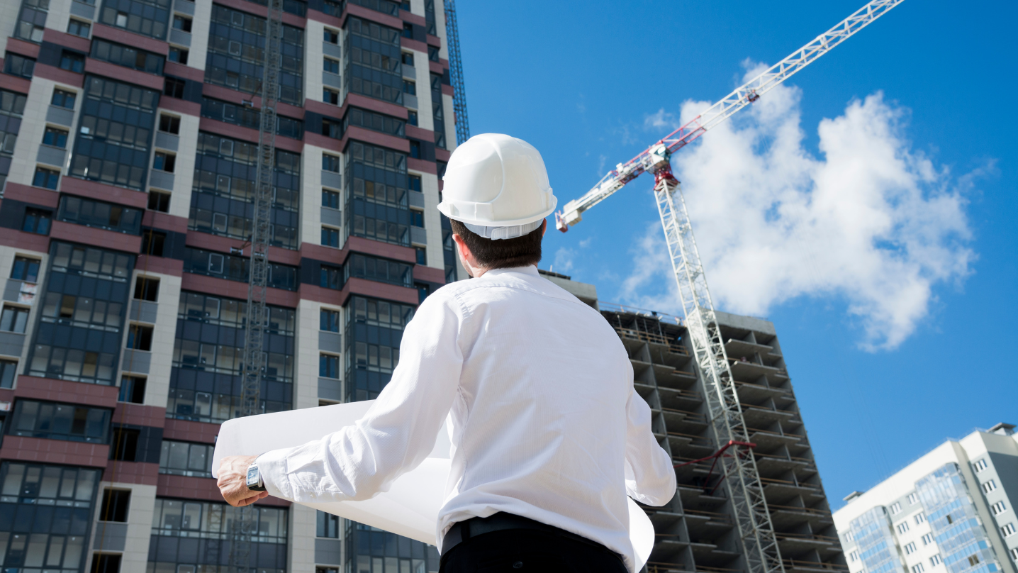 Architect with blueprint looking at a building under construction