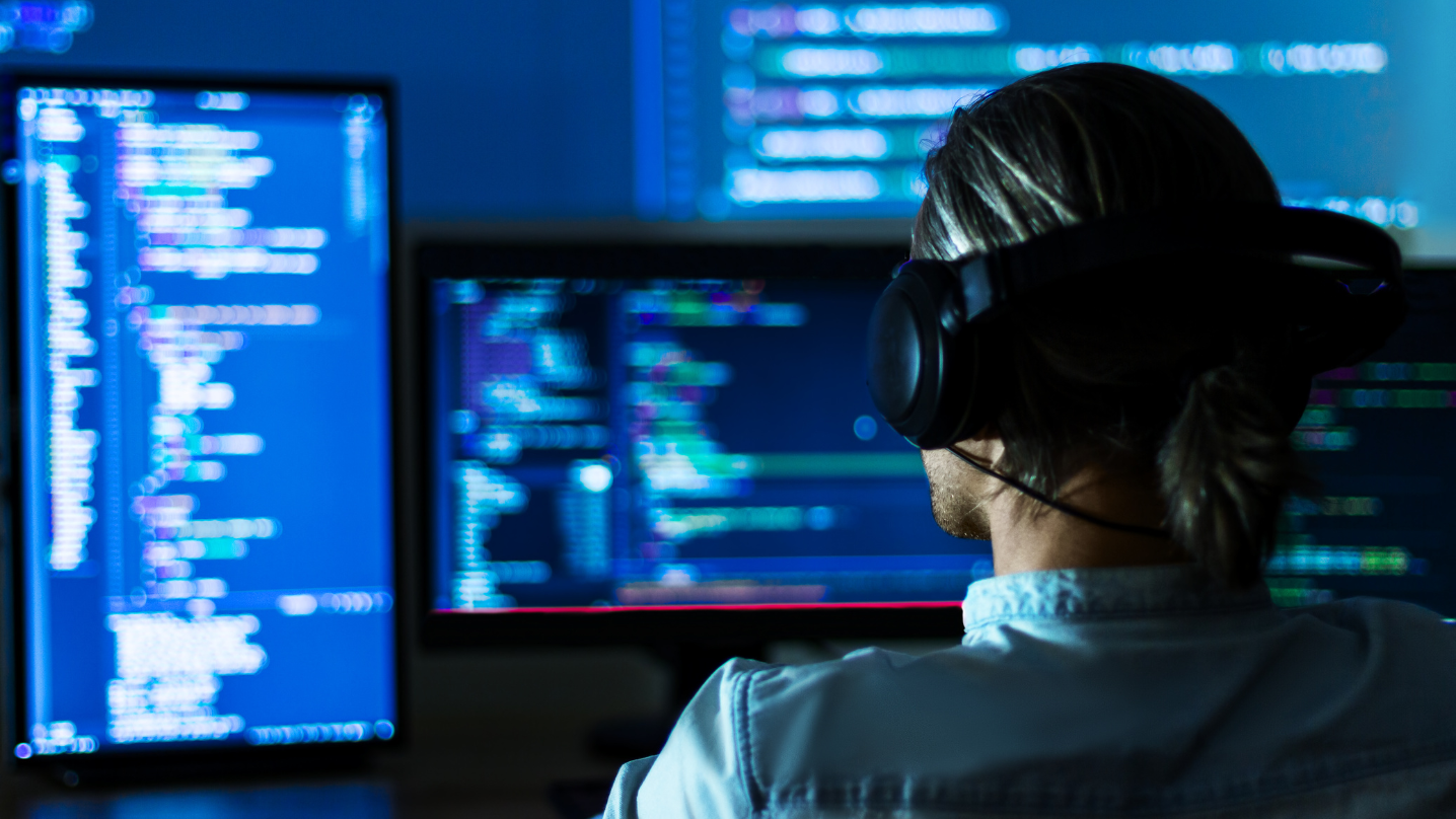 Software developer programming code on multiple screens