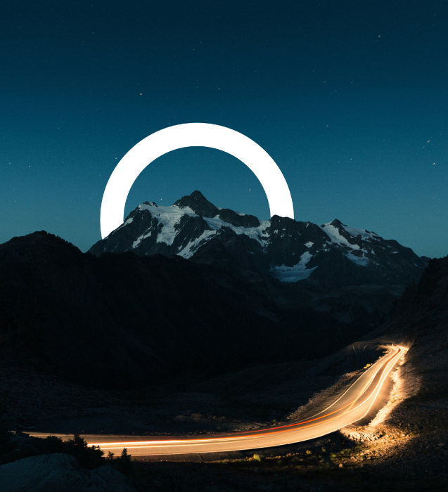 Car trail light on winding road around a mountain at night