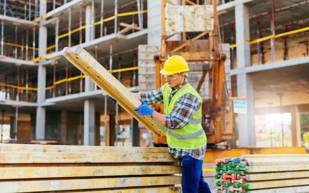 Construction worker stacking wood materials for building project